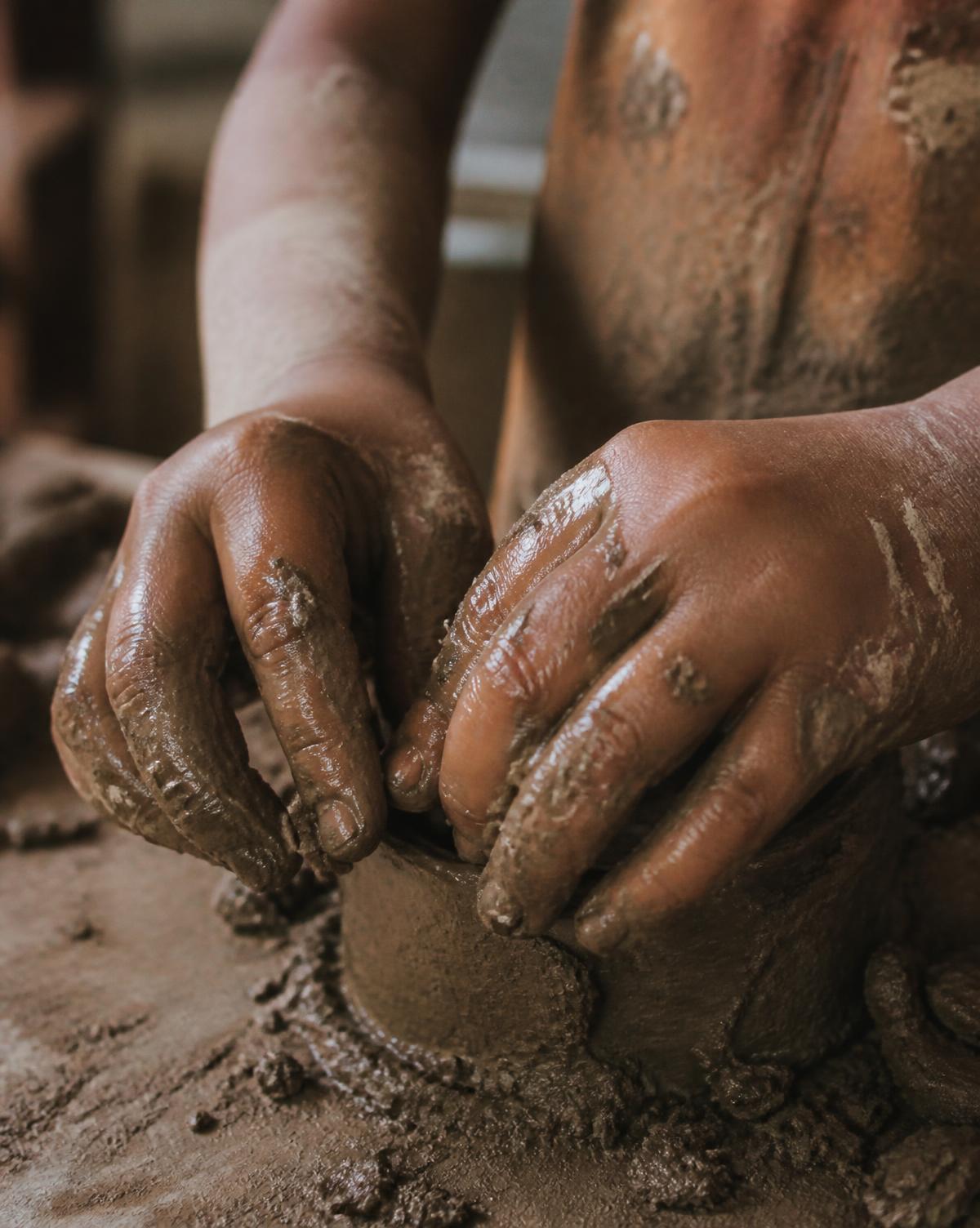 Manos de un niño trabajando con arcilla húmeda